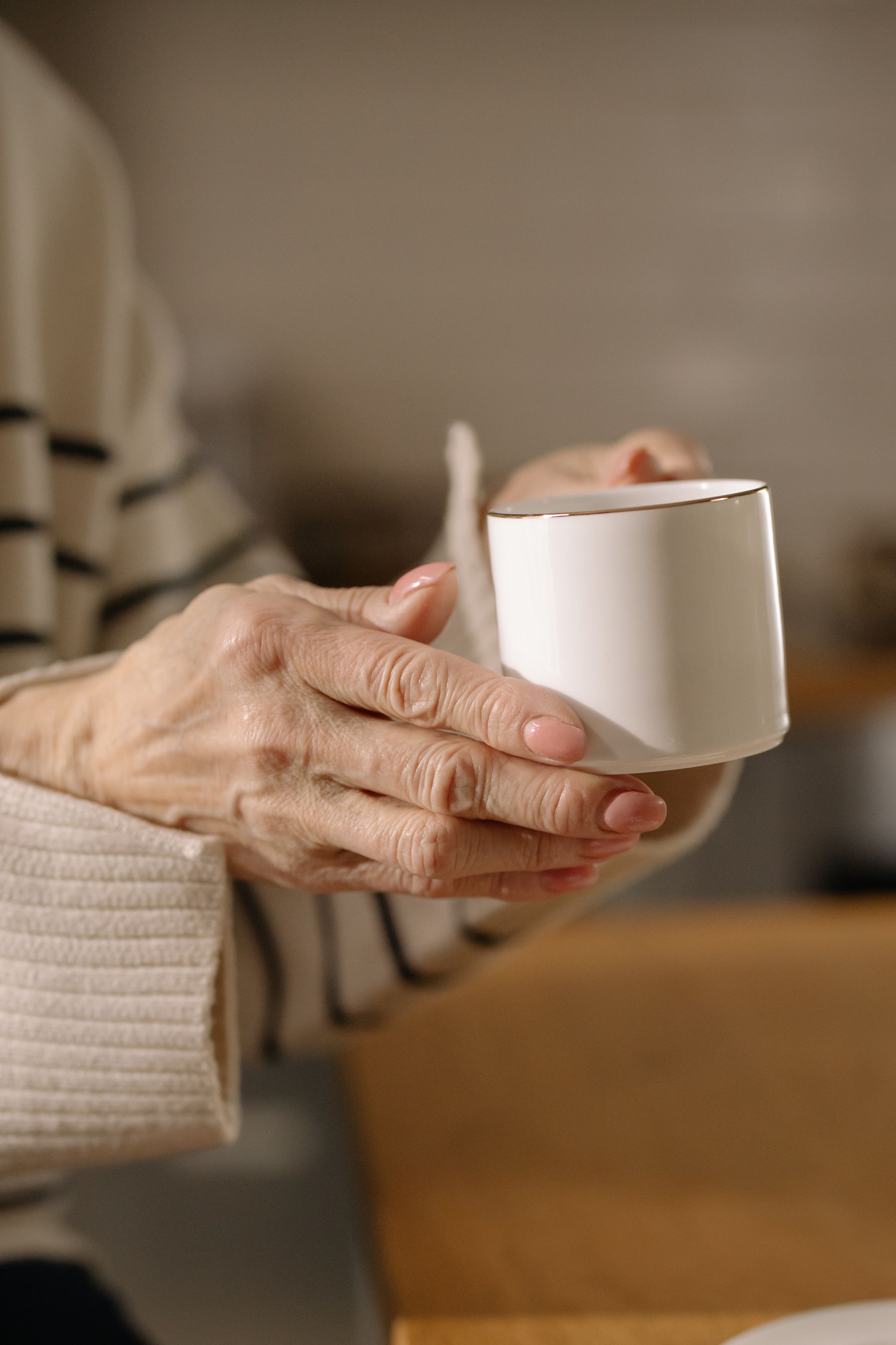 Ältere Hände halten eine Tasse mit heißem Getränk